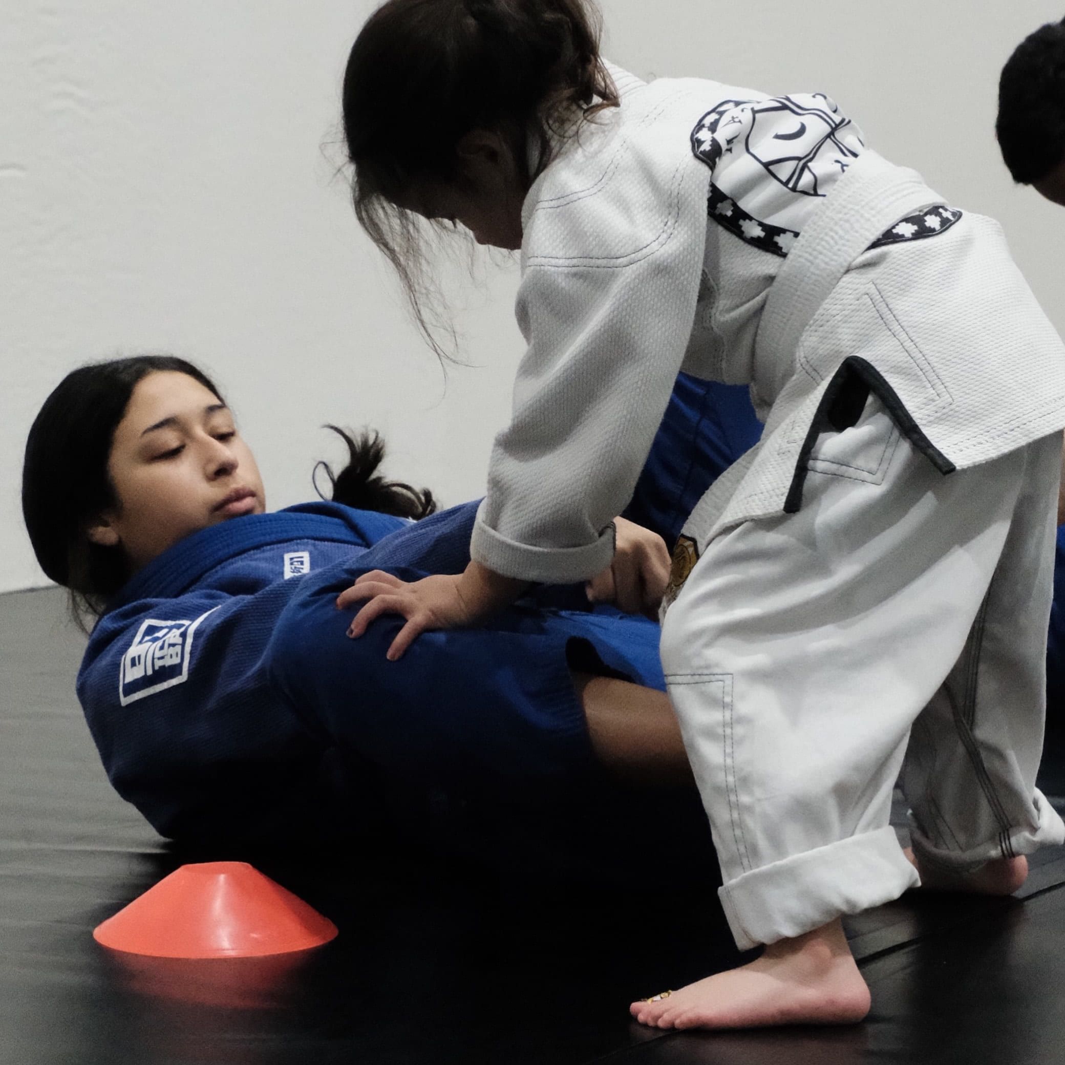 Instructor Missy coaching a young student from guard during a kids class