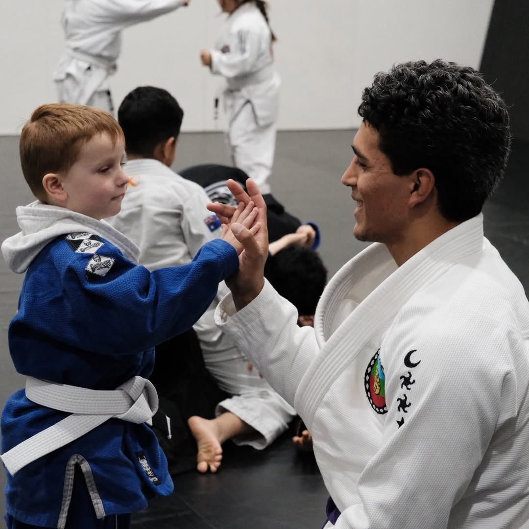 Instructor Ratu high fiving a young student during a kids class