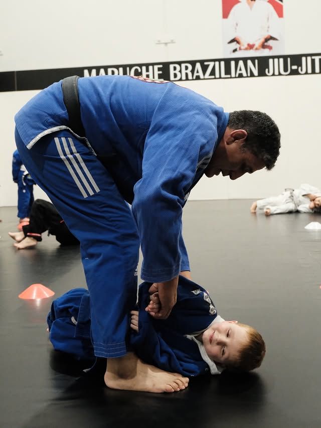 The head instructor coaching a young child on the mat